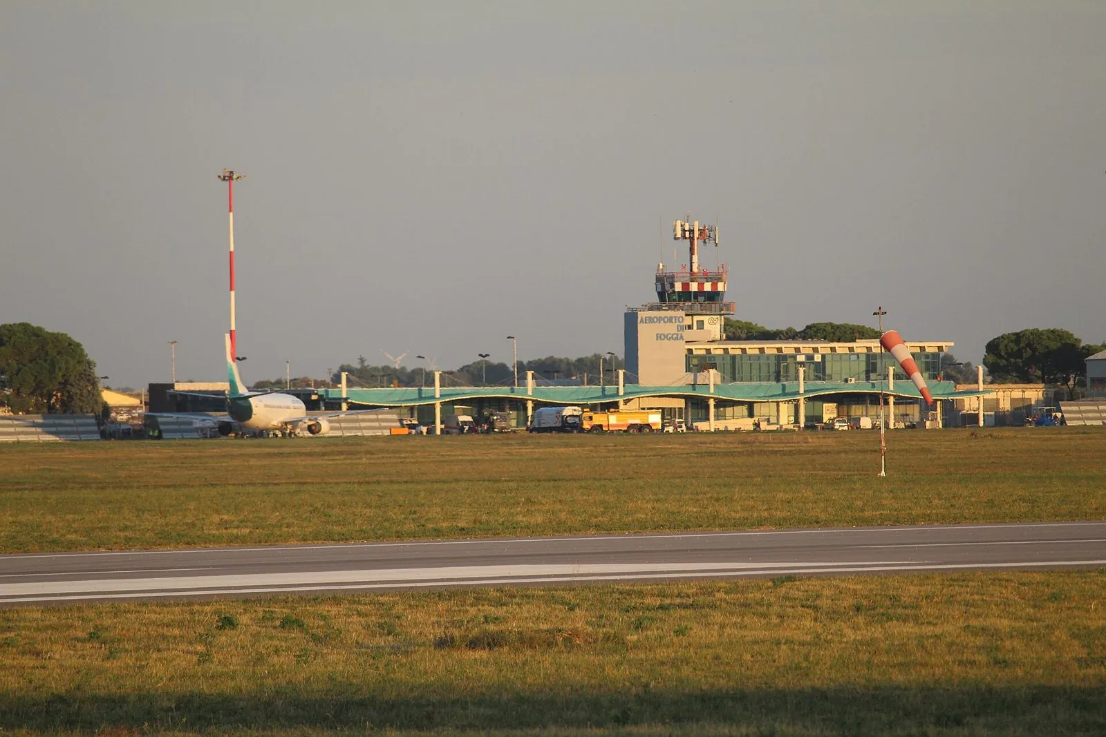 Il terminal e la torre di controllo dell'aeroporto di Foggia Gino Lisa visti dalla pista, con un aereo parcheggiato sul piazzale
