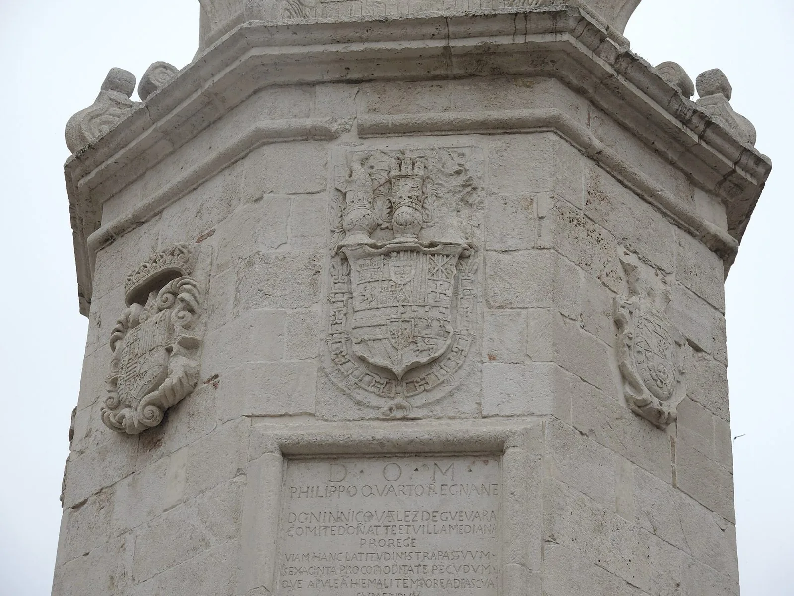 Particolare dell'Epitaffio di Foggia: colonna in pietra chiara con stemmi scolpiti e la lapide latina del 1651 sui tratturi